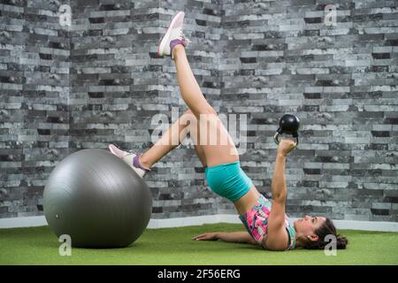 Junge Sportlerin, die im Fitnessstudio mit Kettlebell trainiert Stockfoto