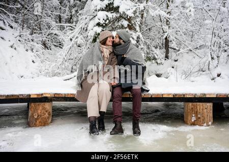 Das Paar schaut sich an, während es auf der Brücke sitzt Wald Stockfoto