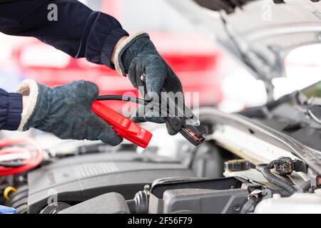 Der Mensch versucht, den Motor mit Überbrückungskabeln in der Nähe zu starten Nach oben Stockfoto