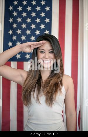 Schöne Frau, die gegen die amerikanische Flagge grüsst Stockfoto