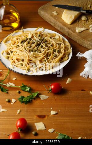 Mann gießt Olivenöl auf Spaghetti in Teller Stockfoto