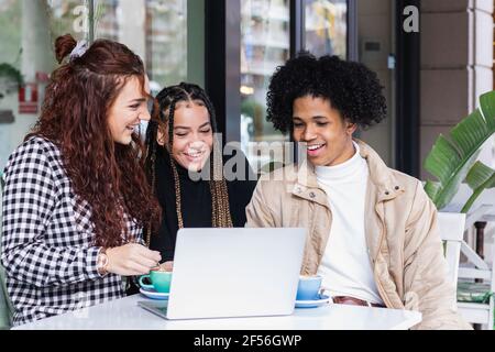 Studenten mit Laptop, während sie zusammen im Straßencafé sitzen Stockfoto