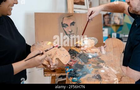 Männlicher Künstler, der Malerei einer Malerin beibringt Stockfoto