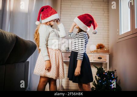 Schwestern gucken sich gegenseitig von den Weihnachtsmützen an Zimmer Stockfoto