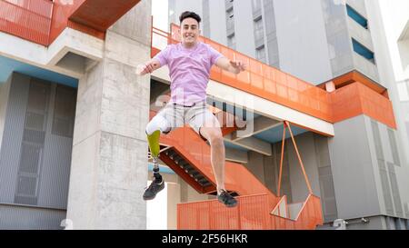 Sorgloser junger Mann mit Amputation springt gegen Gebäude Stockfoto