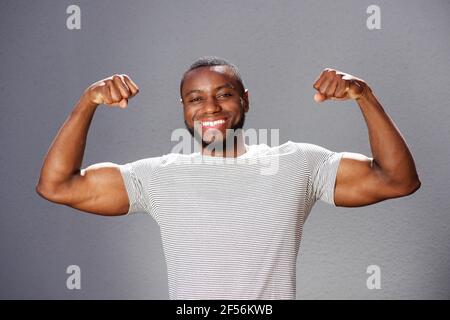 Nahaufnahme Porträt eines jungen lächelnden Mannes, der die Armmuskeln anbiegend Stockfoto