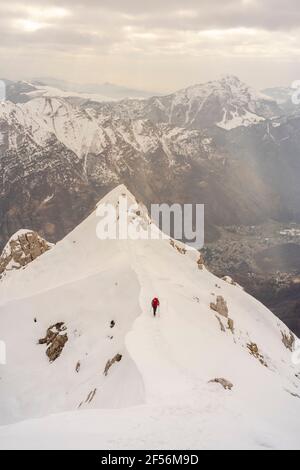 Trekker Walking auf schneebedeckten Berg gegen schöne Bergkette Stockfoto