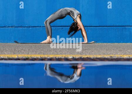 Frau tut zurück beugen Yoga Pose durch blaue Wand Stockfoto
