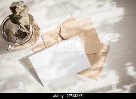 Unbeschriftete Grußkarte Einladung Mockup mit Bastelpapier Umschlag feminin Stillleben Komposition Stockfoto