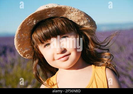 Portrait von niedlichen kleinen Mädchen tragen Strohhut im Freien stehen Stockfoto
