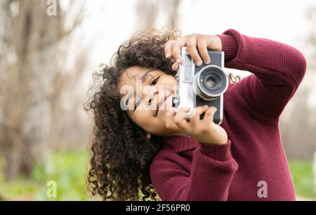 Niedlicher Junge hält Vintage-Kamera in der Natur Stockfoto