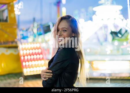 Glückliche junge Frau auf einer Kirmes in der Nacht Stockfoto