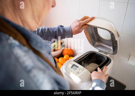 Älterer Mann, der zu Hause Brot im Gerät zubereitete Stockfoto