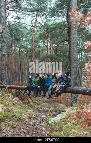 Gruppe von Wanderern, die im Herbst auf einem umgestürzten Baum sitzen Wald Stockfoto