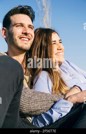Fröhliche Frau, die mit dem Mann im Park sitzt Stockfoto