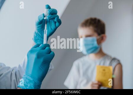 Injektionsspritze mit COVID-19-Impfstoff für Jungen im Hintergrund In der Klinik Stockfoto