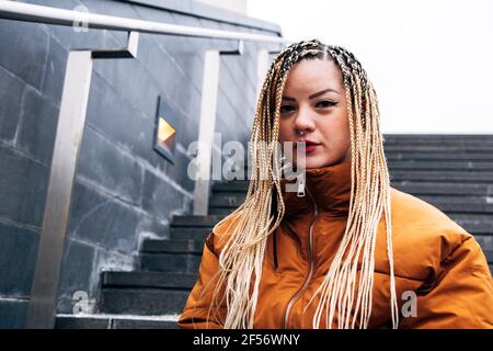 Junge Frau in Jacke starrte, während sie auf der Treppe stand Stockfoto