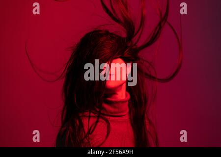 Frau wirft Haare auf roten Hintergrund Stockfoto