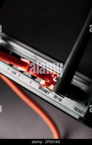 Das rote Patchkabel wird in den WLAN-Port des Routers gesteckt, um auf das Internet zuzugreifen. Internetverbindung über ein Kabel mit einem Router. Stockfoto