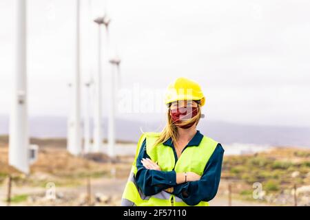 Vorderansicht einer jungen Ingenieurin, die in einem Windturbinenpark arbeitet. Saubere Energie, erneuerbare Energie und Umweltkonzept. Stockfoto