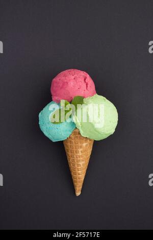 Buntes Eis im Waffelkegel auf schwarzem Hintergrund. Position vertikal. Nahaufnahme. Stockfoto