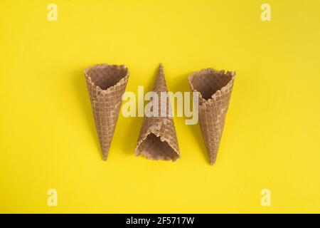 Blick von oben auf Waffel-Eiszapfen auf dem gelben Hintergrund. Nahaufnahme. Speicherplatz kopieren. Stockfoto
