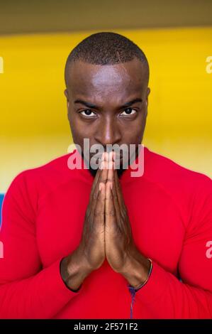 Vertikale Nahaufnahme des schwarzen afrikanischen Menschen konzentriert und fokussiert mit verbundenen Händen Vorbereitung für einen Wettbewerb und Blick nach vorne. Stockfoto