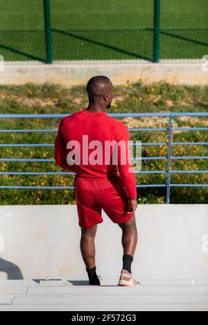 Vertikale Rückansicht des athletischen muskulösen schwarzen Mannes mit Sportkleidung, die unten geht. Stockfoto
