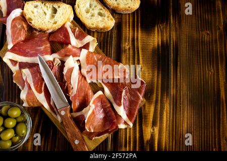 Spanisches Jamon im Schneidebrett auf braunem Holzhintergrund.Draufsicht. Stockfoto