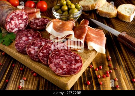 Spanische Jamon und Wurst in der Schneidebrett auf der Brauner Holzhintergrund Stockfoto