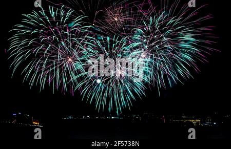 Aqua und lila Feuerwerk erleuchtet den Nachthimmel über Parliament Hill - ein Vollmond guckt durch Stockfoto