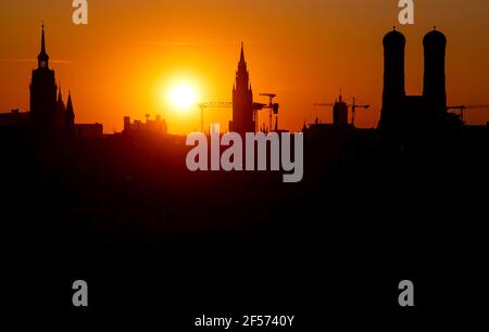 München, Deutschland. März 2021, 24th. Die Sonne untergeht hinter der Skyline der bayerischen Hauptstadt. Von links nach rechts sind die Türme der Peter-Kirche (Alter Peter), das Rathaus und die Frauenkirche zu sehen. Quelle: Sven Hoppe/dpa/Alamy Live News Stockfoto