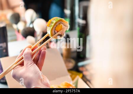 Schöne junge Frau, die Sushi-Rolle im Café isst. Frau essen Sushi-Set mit Essstäbchen im Restaurant Stockfoto