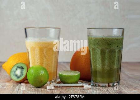 Zwei große Gläser mit Kiwi und Spinat Smoothies umgeben von Früchten auf einem Holztisch. Das Konzept der Gewichtsabnahme und die richtige Ernährung Stockfoto