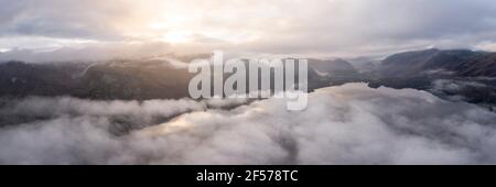 Luftpanorama von Dewentwater bedeckt in Nebel bei Sonnenaufgang Stockfoto