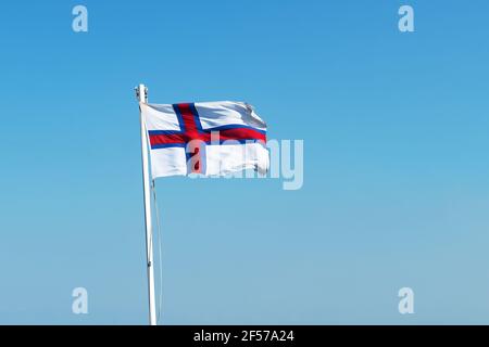 Flagge der Färöer Inseln auf blauem Himmel Hintergrund Stockfoto