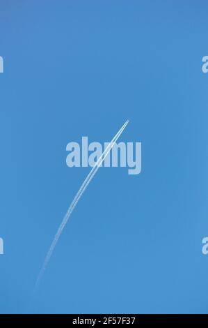 Kopieren Sie das Raumbild des von einem Flugzeug hinterließenden Contrails Gegen den blauen Himmel auf internationaler Reise Stockfoto