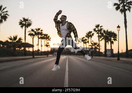 Junger stilvoller europäischer Mann, der auf der Straße springt Stockfoto