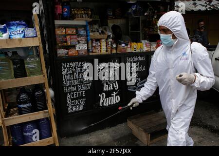 Sucre, Venezuela. März 2021, 24th. Das Gesundheitspersonal des Bürgermeisters von Sucre sprüht eine Lösung aus Hypochlorit und Wasser, um eine Infektion mit Covid-19 in einem Geschäft zu verhindern, in dem Lebensmittel, Reinigungsmittel und Schmiermittel für Fahrzeuge verkauft werden. Kredit: Jesus Vargas/dpa/Alamy Live Nachrichten Stockfoto