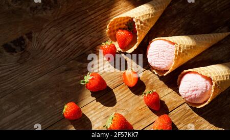 Erdbeereis in einem Waffelkegel. Rote Beeren und Eiskugeln Stockfoto