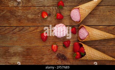 Erdbeereis in einem Waffelkegel. Rote Beeren und Eiskugeln Stockfoto