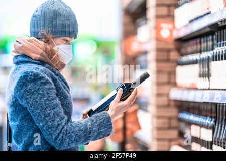 Junge Frau wählt Wein in einem Weinladen Stockfoto