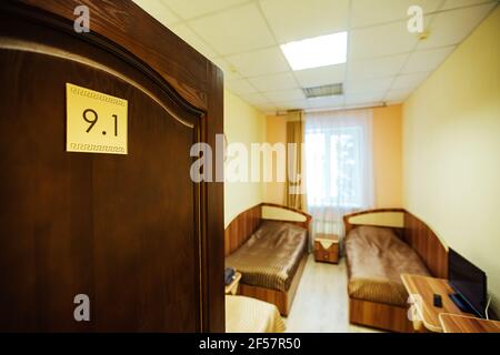 Ein Zimmer in einem billigen Hotel. Minimalistisches Interieur eines Economy Class Hotelzimmers. Übernachtung für den Reisenden. Mehrere Betten und ein Tisch Stockfoto