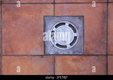 Blick von oben auf einen Metallabfluss zum Ableiten von Regenwasser In der Terrasse von Lichtern eines Hauses Stockfoto