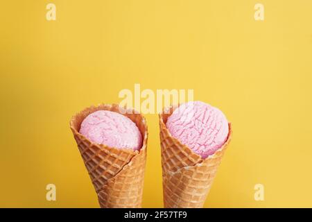Köstliches rosa Eis in einem Kegel auf gelbem Hintergrund. Stockfoto