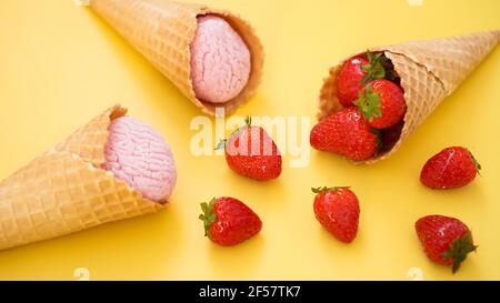 Erdbeereis in einem Waffelkegel. Eis und Beeren auf einem gelben Stockfoto