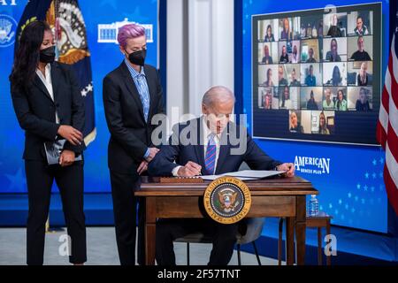 Washington, Usa. März 2021, 24th. US-Präsident Joe Biden, mit Margaret Purce (L), Megan Rapinoe (C) und anderen Mitgliedern der US-Fußballnationalmannschaft WomenÕs, unterzeichnet eine Proklamation während einer Veranstaltung zum Tag der Entlohnung im Staatlichen Speisesaal des Weißen Hauses in Washington, DC, USA, 24. März 2021. Equal Pay Day markiert die zusätzliche Zeit, die es dauert eine durchschnittliche Frau in den Vereinigten Staaten, um den gleichen Lohn zu verdienen, dass ihre männlichen Kollegen im vorherigen Kalenderjahr. Quelle: SIPA USA/Alamy Live News Stockfoto