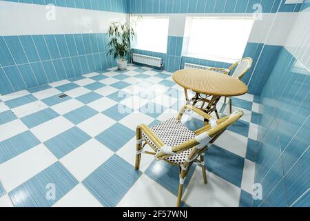 Holzstühle auf dem gefliesten Boden. Ein Sitzbereich für Gäste in der Nähe des Pools im Spa-Komplex Stockfoto