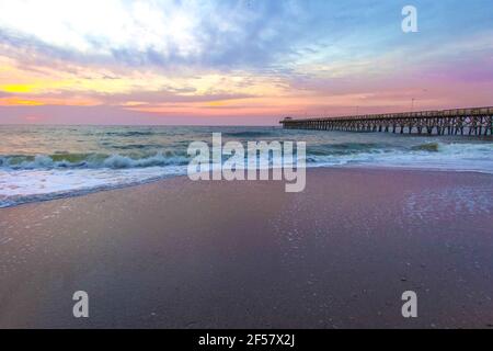 Myrtle Beach Landschaft Bei Sonnenaufgang. Sonnenaufgang an einem breiten Sandstrand mit Angelpier an der Küste des Atlantischen Ozeans in Myrtle Beach, South Carolina, USA Stockfoto