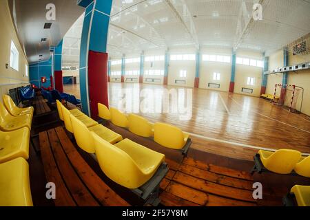 Farbige steht für Fans in einem Hallenstadion. Sitze in der Sporthalle für Wettkämpfe. Leere Bank von Reservespielern Stockfoto